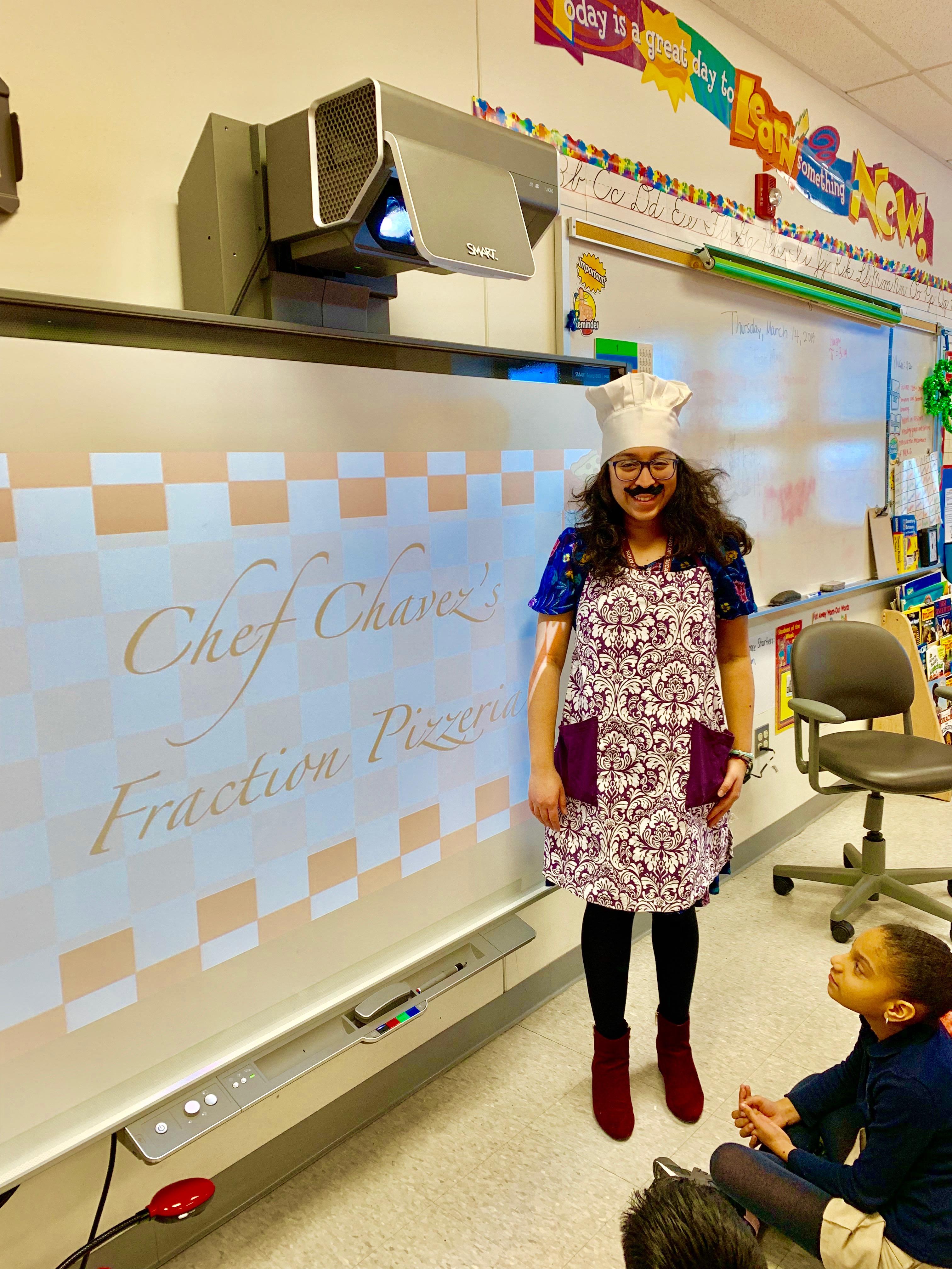 Mrs. Chavez 3rd Grade class. She's wearing a chef's hat with a mustache and red and white apron