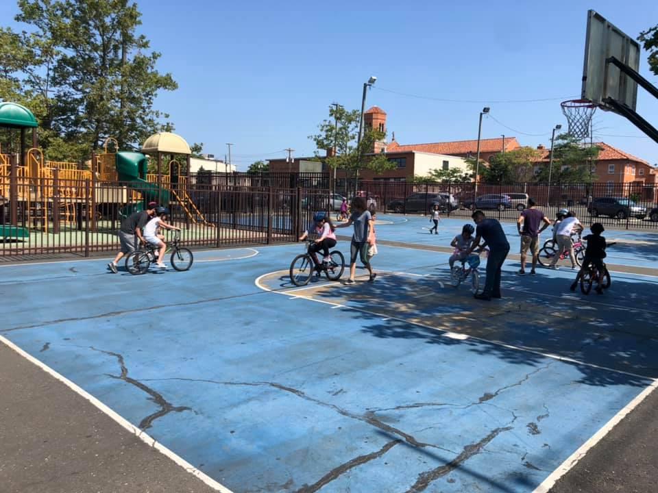group of children accompanied by adults learning to ride their bikes