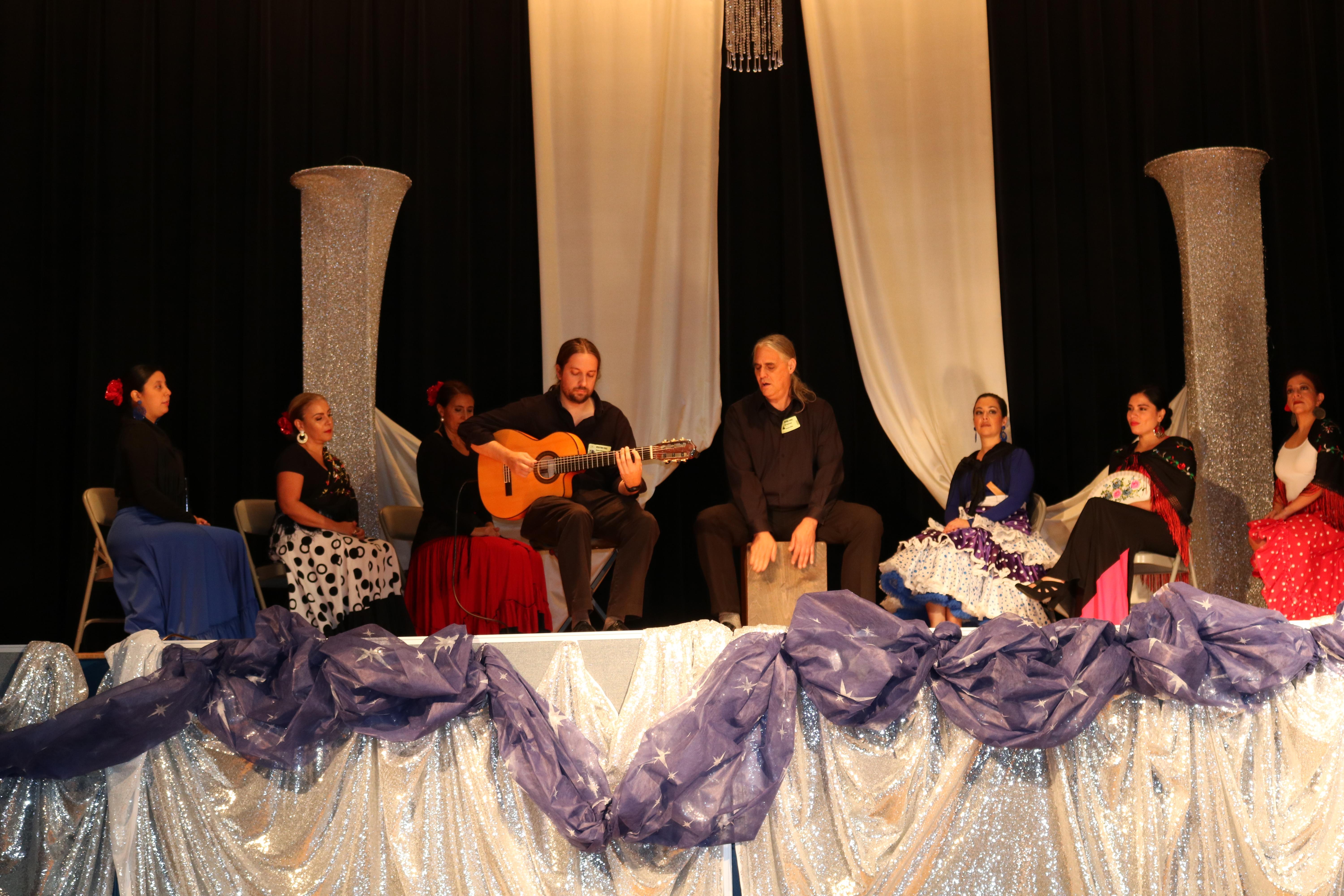 CP teachers in flamenco costumes accompanying two musicians one with a guitar and the other the mambo drum