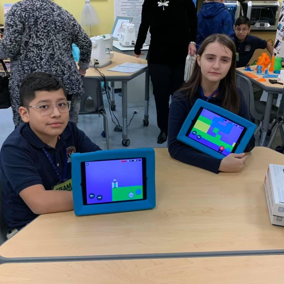 two students showing off their coding on ipads in the STEM lab